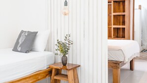 Un dormitorio con una cama, una mesita de noche con un florero y un banco de madera.