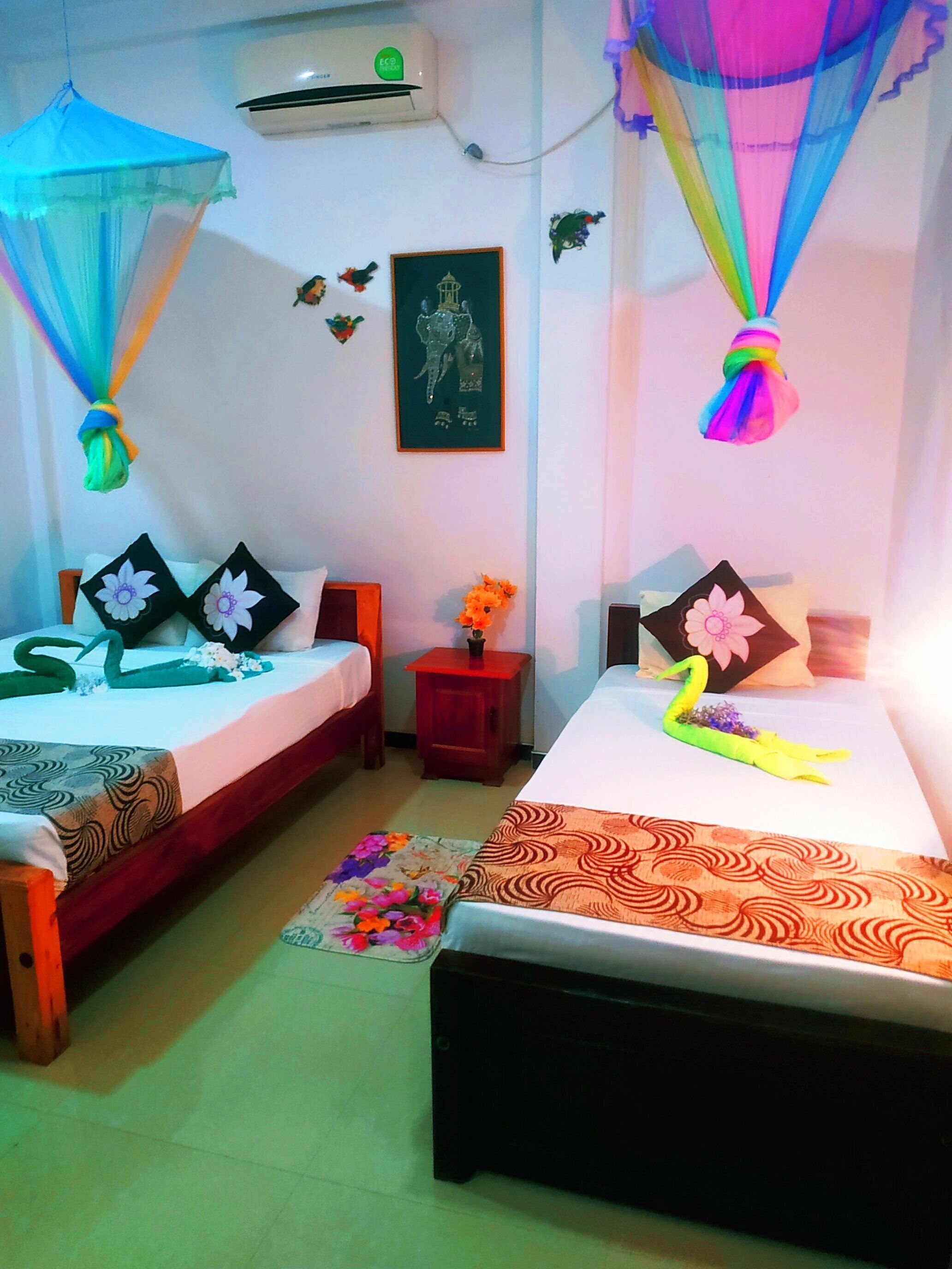 Habitación con dos camas, cada una con dosel. Hay una mesita con un florero y un cuadro en la pared.