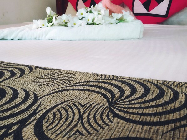 A bed with a white sheet and a decorative pillow with a red and black geometric pattern. - Green Heaven Safari Resort Udawalawa (Udawalawa)
