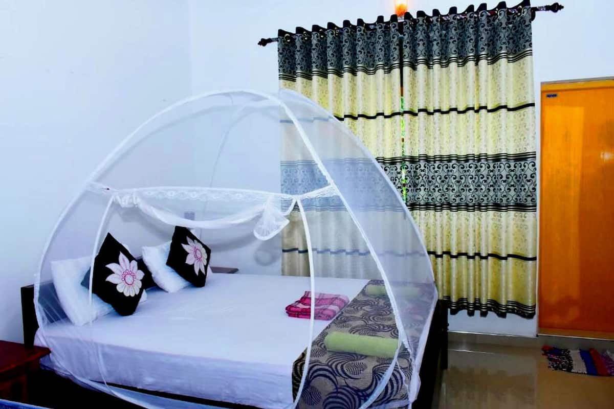 Ein Zimmer mit einem Bett, das unter einem Moskitonetz hängt, einem Vorhang und einer Tür.