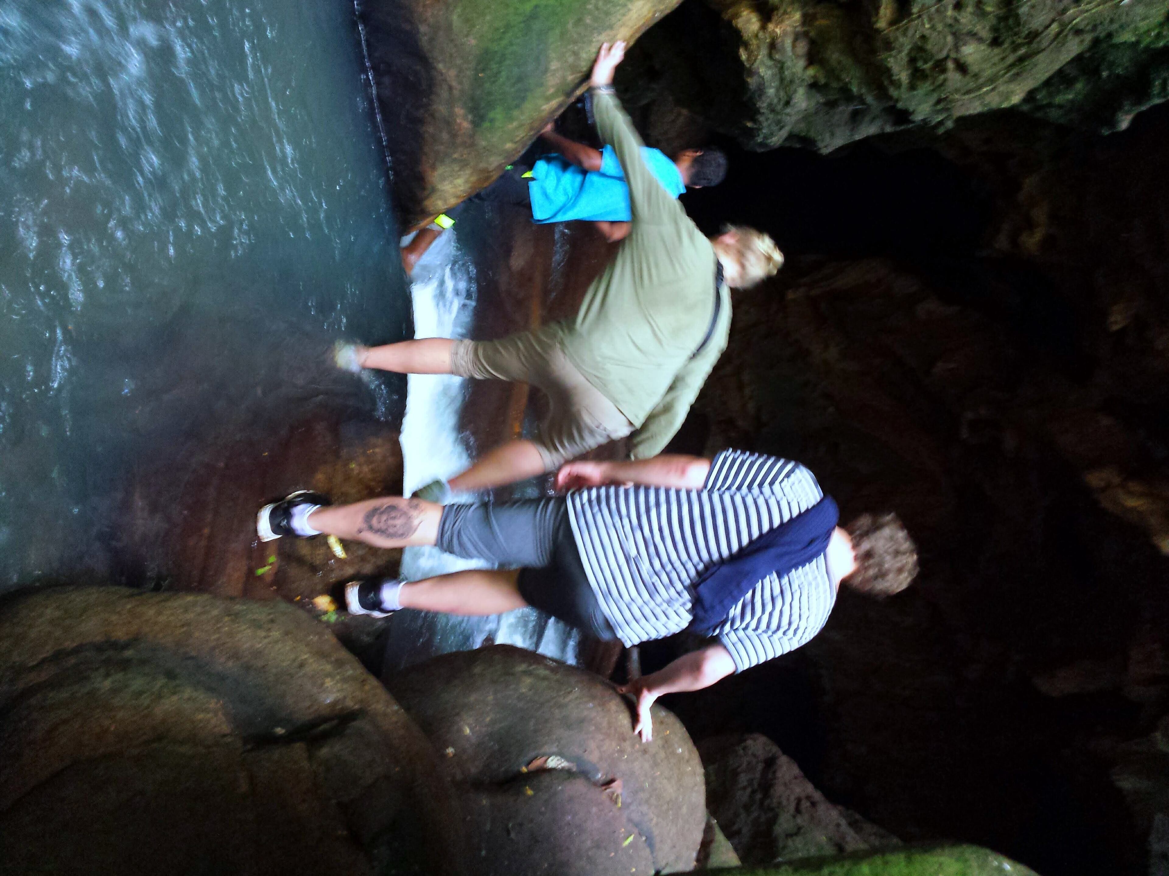 Un gruppo di persone in piedi su rocce vicino a un corso d'acqua in un ambiente simile a una grotta.