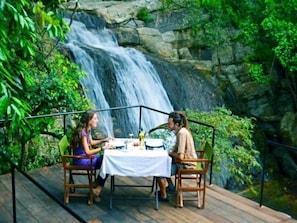 Two people dining at a table with a waterfall view.