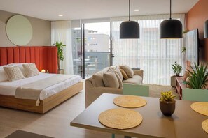 Une chambre d’hôtel moderne équipée d’un lit, d’un canapé, d’une table à manger et d’un balcon avec vue.
