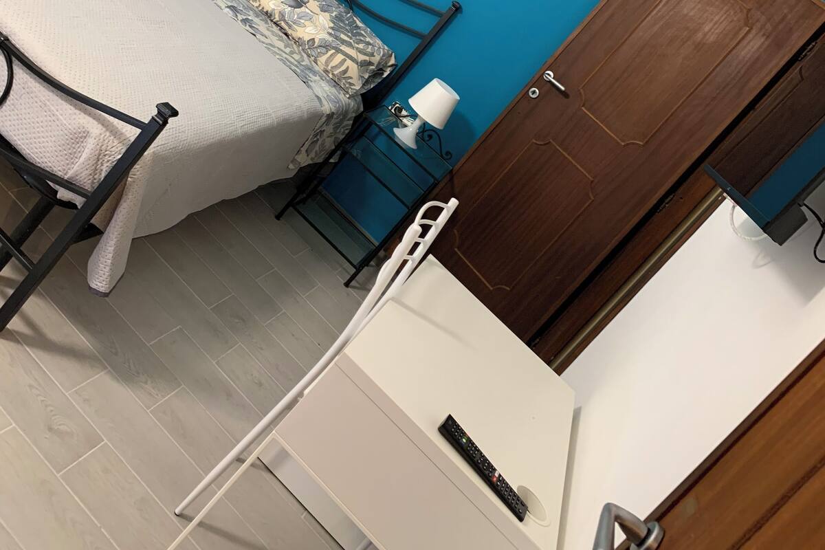 A room with two beds, a desk, a chair, a lamp, and a door.