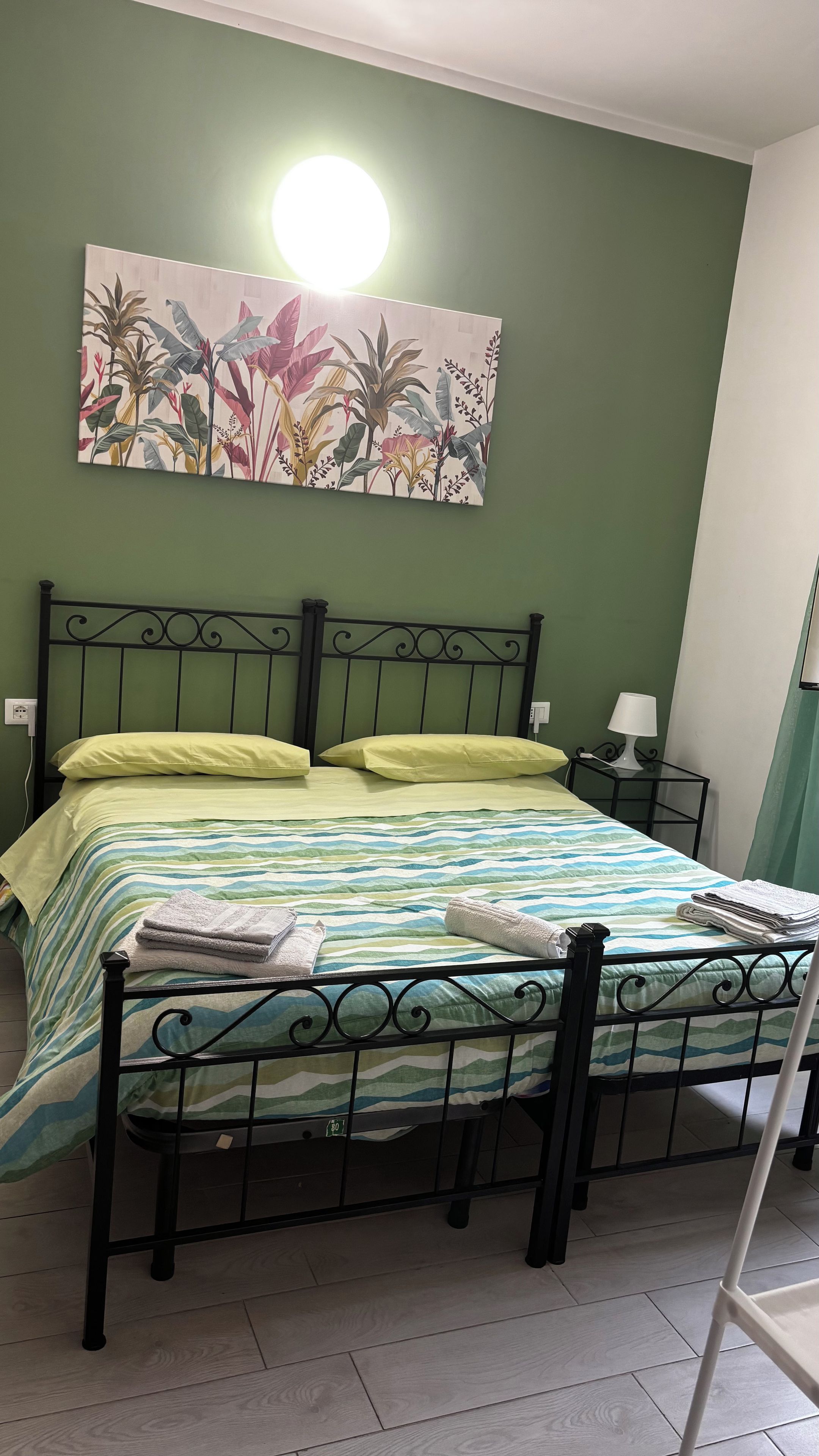 Una camera da letto con un letto, un comodino, una lampada e un quadro appeso al muro.