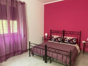 A bedroom with a bed, curtains, a nightstand, and a lamp. - B&B Sole e Luna (Rome)