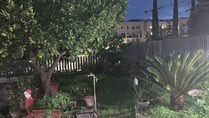 Een tuin met potplanten, een standbeeld en een boom met fruit.
