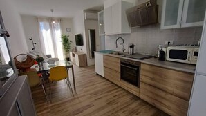 A modern kitchen with wooden cabinets, a built-in oven, a microwave, and a sink. - Il Polpoleo apt in Portoazzurro,400mt Dalla Spiaggia, 900mt dal Centro,wifi (Porto Azzurro)