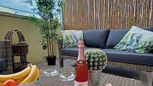 A wicker table with a bottle of Veuve Clicquot champagne, glasses, bananas, oranges, and a cactus plant. - Il Polpoleo apt in Portoazzurro,400mt Dalla Spiaggia, 900mt dal Centro,wifi (Porto Azzurro)