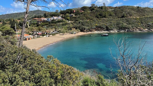 A coastal area with a sandy beach, clear blue water, and a hillside with buildings. - Il Polpoleo apt in Portoazzurro,400mt Dalla Spiaggia, 900mt dal Centro,wifi (Porto Azzurro)
