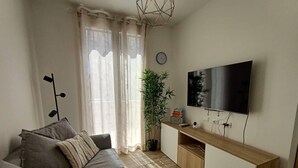 A modern living room with a sofa, a TV, a plant, and a wooden console table. - Il Polpoleo apt in Portoazzurro,400mt Dalla Spiaggia, 900mt dal Centro,wifi (Porto Azzurro)