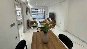 A modern living room with a wooden dining table, a sofa, and a TV.