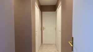 A hallway with marble flooring, brown walls, and white doors with gold handles.