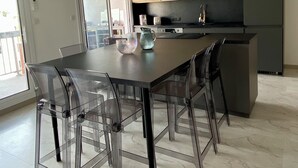 A modern kitchen with wooden cabinets, a black refrigerator, and a dining area with a glass table and chairs.