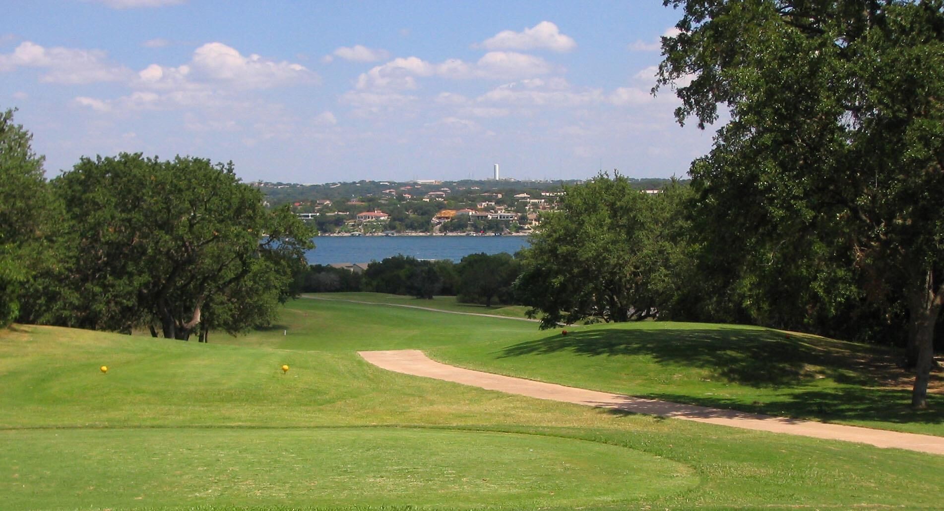 A golf course with a clear view of a lake and distant buildings.