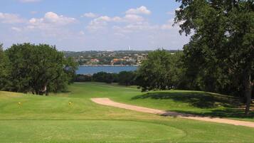 A golf course with a clear view of a lake and distant buildings.
