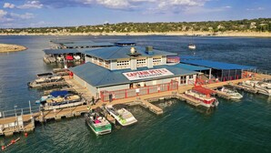 A boat house with a sign reading "Captain Pete's Boathouse" featuring a marina with several boats docked. - Stylish Lake Travis Getaway! Beach Access, Poker & VR (Lago Vista)