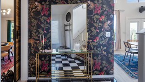 A room with a checkered floor, a glass table with gold legs, and a mirror reflecting a staircase. - Stylish Lake Travis Getaway! Beach Access, Poker & VR (Lago Vista)