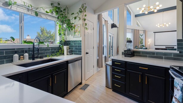 A modern kitchen with black cabinets, a white countertop, and a large window. - Stylish Lake Travis Getaway! Beach Access, Poker & VR (Lago Vista)