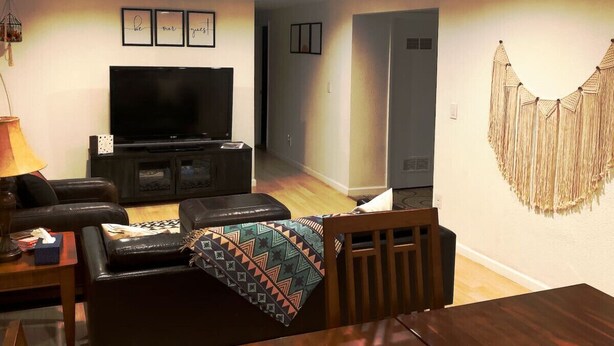 Sala de estar com televisão, sofá de couro e mesa de jantar.