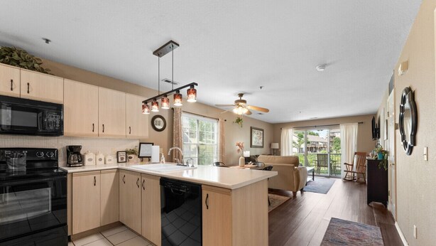 Une cuisine moderne dotée d’un îlot central, d’appareils électroménagers noirs et d’un ventilateur de plafond.