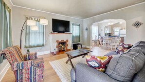 A living room with a fireplace, sofa, armchair, and a dining area in the background. - Golden Luxe Bungalow | Walk to Downtown & Parks (Golden)
