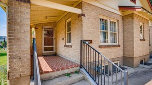 A two-story house with a brick exterior, a covered porch, and a small front yard. - Golden Luxe Bungalow | Walk to Downtown & Parks (Golden)