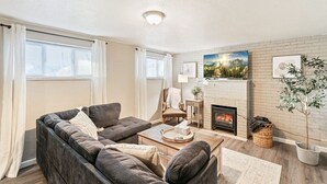 Un salon chaleureux avec un canapé, des fauteuils, une cheminée et un grand tableau accroché au mur.