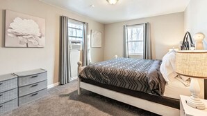 Une chambre à coucher avec un lit, une lampe de chevet et une commode.