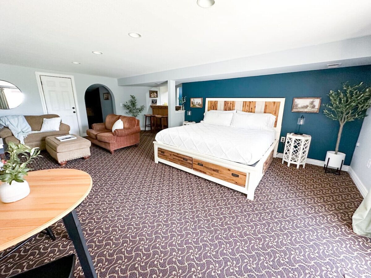 A bedroom with a large bed, a sofa, a coffee table, and a potted plant.