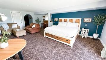 A bedroom with a large bed, a sofa, a coffee table, and a potted plant.