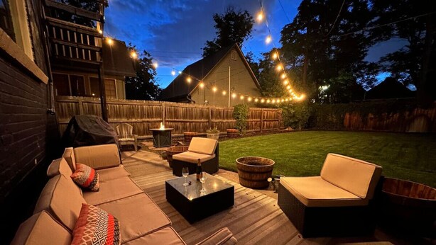 Un patio al aire libre con un conjunto de sofás, una mesa de centro y luces colgantes.