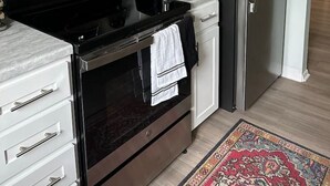 A modern kitchen with white cabinetry, a stainless steel refrigerator, a microwave, a stove, and a toaster. - Lakewood Gem: Furnished Haven! Perfect for Month Long Stays! (Lakewood)