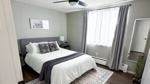 Un dormitorio moderno con cama, ventilador de techo, mesita de noche y alfombra grande.