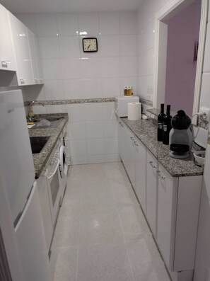 Kitchen area features a sink with faucet and dish rack, along with a coffee maker and wine bottles.