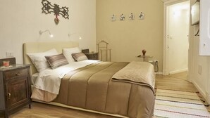 Une chambre à coucher bien aménagée, avec un grand lit, des tables de chevet, une petite table d’appoint et une étagère fixée au mur.