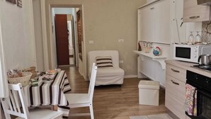 Un espace de vie compact comprenant un coin cuisine, un coin repas avec des chaises à rayures et un canapé.