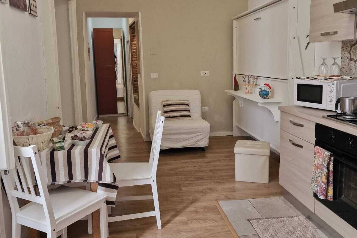 A compact living space with a kitchenette, a dining area with striped chairs, and a sofa.