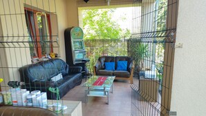 A living room with a black leather sofa, a brown leather sofa, and a glass coffee table. There is a TV on a stand and a plant in the corner.