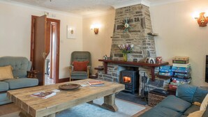 A cozy living room with a stone fireplace, a wooden table, and a comfortable sofa. - Elmtree Cottage, Cardigan (Cardigan)