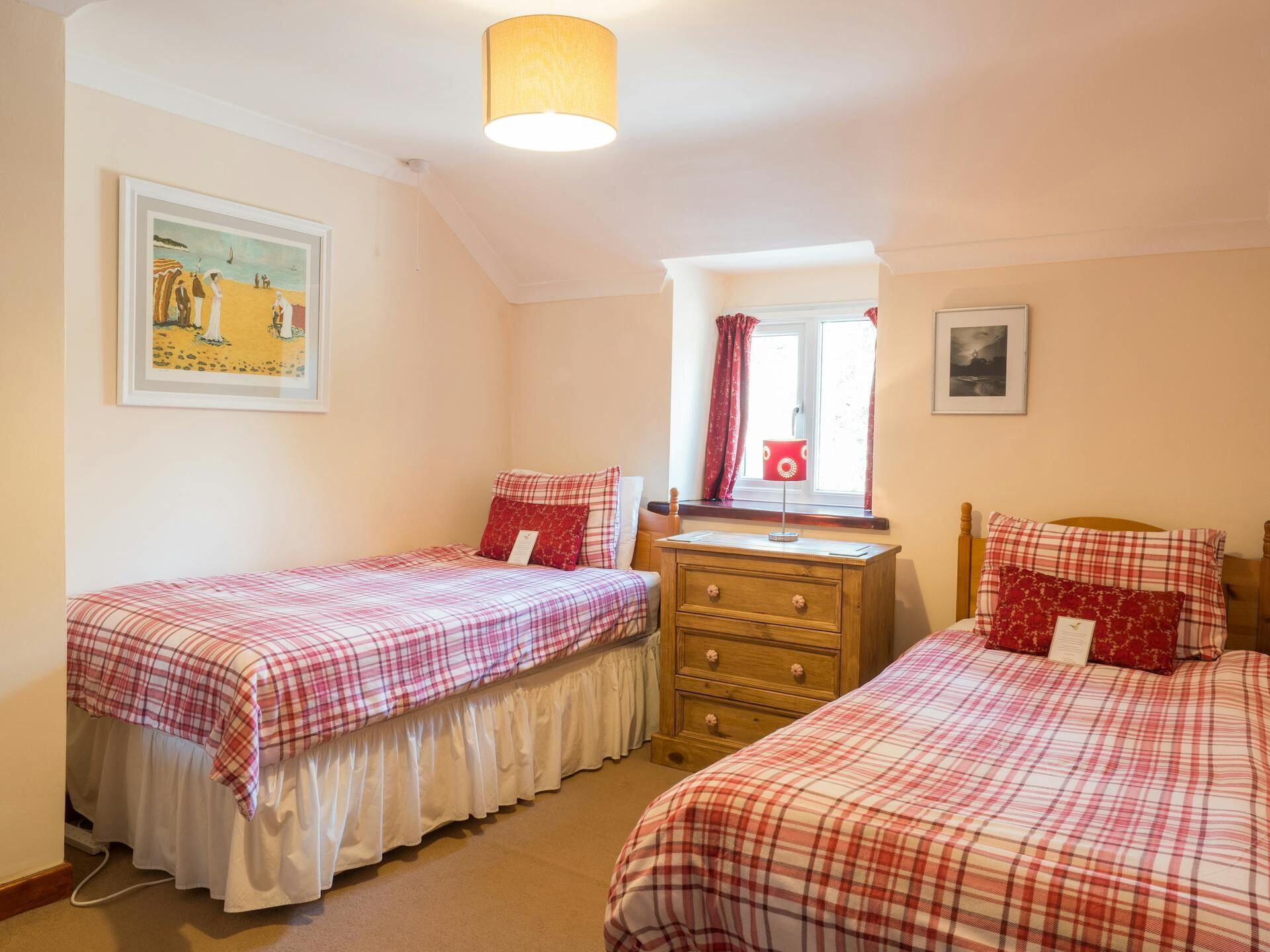 A bedroom with two beds, a dresser, a window with curtains, and a painting on the wall.