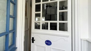 Une porte blanche avec une enseigne bleue portant l’inscription « Morwylfa » et un loquet noir.