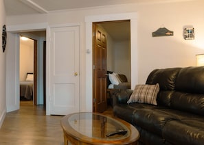 A living room with a leather sofa, a glass coffee table, and a door leading to another room. - The Catch & Rest – 3BR Mobridge Stay (Mobridge)