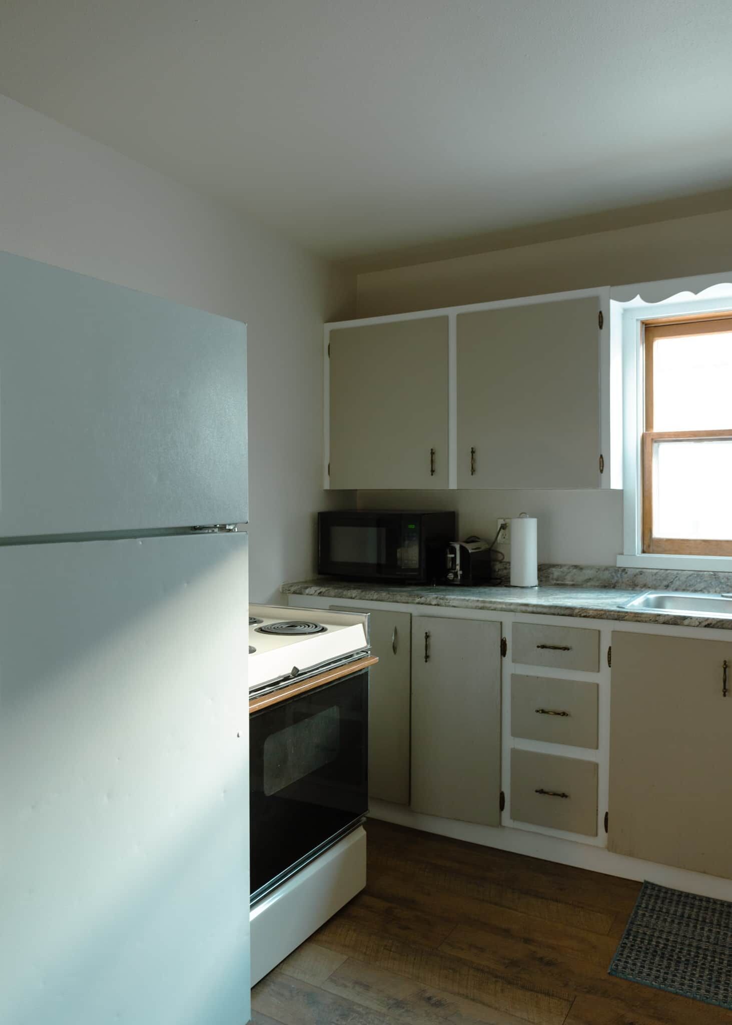 Una cocina funcional con refrigerador, estufa, microondas y gabinetes.