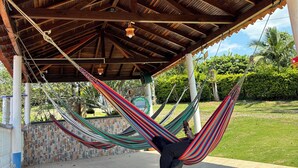 A hammock under a wooden pavilion with a tiled floor and a stone wall. - FINCA VACACIONAL GUANANI (Socorro)