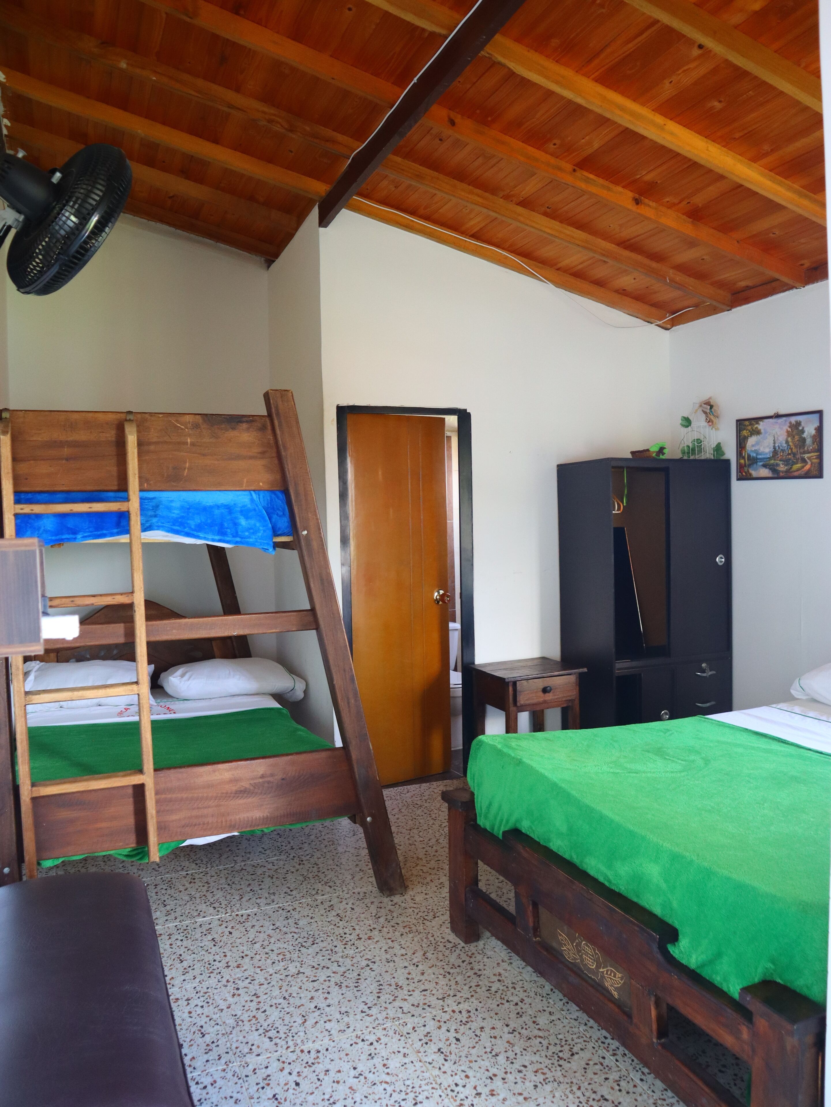 A room with a bunk bed, a desk, a wardrobe, and a door.