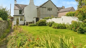 A two-story house with a well-maintained garden and a stone wall. - Llys Owain, comfortable Cottage - Pass the Keys (Amlwch)