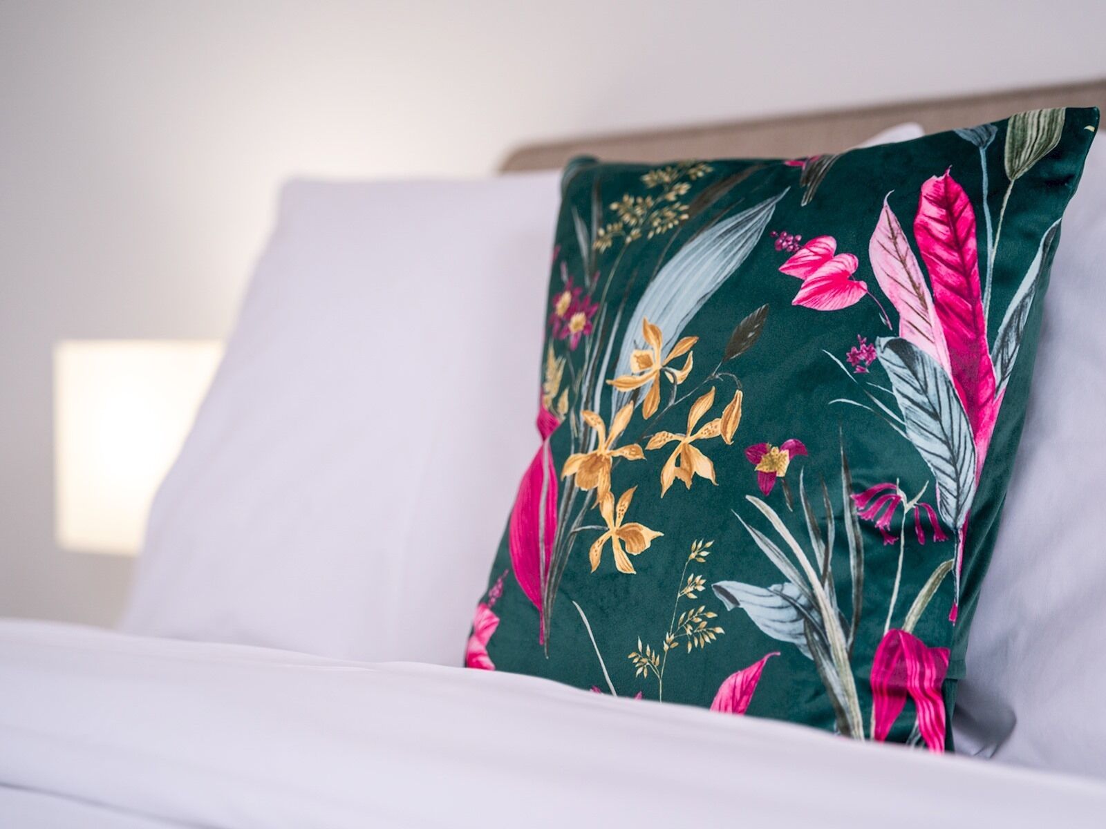 A bed with a white sheet and a pillow featuring a floral pattern.