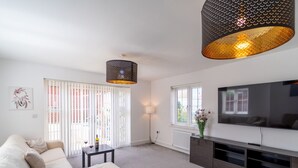 Een moderne woonkamer met een bank, een salontafel, een televisie en een decoratieve lamp.