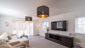 Een moderne woonkamer met een zithoek, een televisie, een console tafel en een decoratieve lamp.